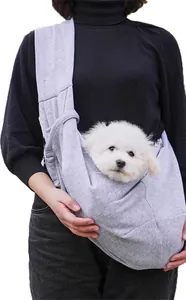 Modelo llevando un cachorro blanco en una cómoda bandolera gris para mascotas pequeña