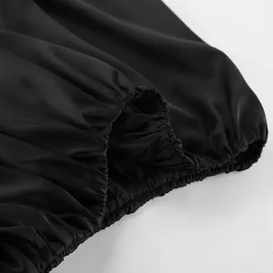Détail de l'ourlet élastique froncé sur un haut élégant en satin noir brillant