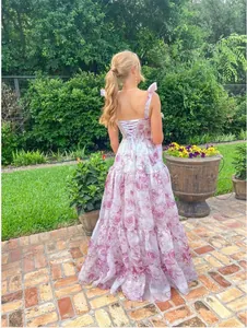 Back view of elegant floral organza long dress with lace-up detail in a lush garden setting.