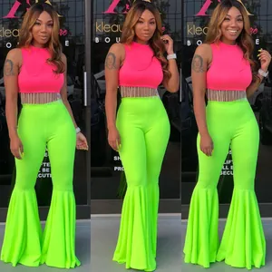 Conjunto sexy con top corto de flecos rosa y pantalones de campana con volantes verde.