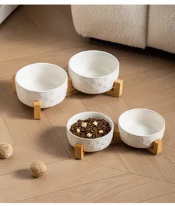 Minimalist white ceramic pet bowl with paw prints and bamboo stand for cats and dogs.