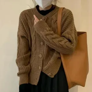 Detail view of a cozy brown cable-knit crewneck cardigan with loose long sleeves.