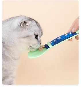 Gros plan d'un chat mangeant avec une cuillère pressoir vert clair pour friandises