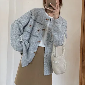 Detalle de una rebeca gris de cuello redondo con botones de cuerno y bordados florales.