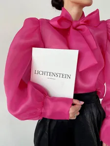 Elegante blusa de malla rosa fucsia con mangas abullonadas y gran lazo decorativo al cuello