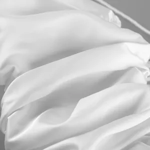Detailed close-up of elegant white satin fabric showing smooth texture and soft drapes
