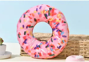 Detailed view of a pink plush donut dog toy with sprinkles on a woven basket background.