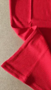 Macro view showing the detailed red ribbed fabric texture and hemline of a women's T-shirt
