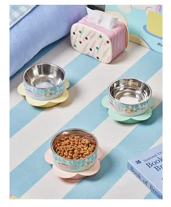 Detail of three colorful flower-shaped stainless steel pet bowls on a blue striped rug.
