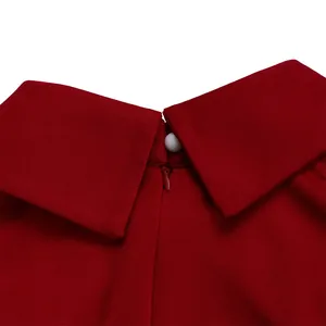 Close-up of red dress collar detail with white pearl button and hidden back zipper