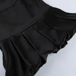 Close-up view of a black satin camisole featuring delicate ruffled hem and smooth silk-like fabric.