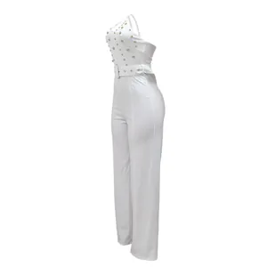 Side view of elegant white one-shoulder jumpsuit featuring gold stud embellishments