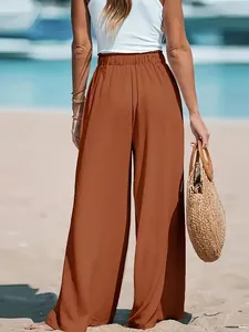 Back view of woman wearing terracotta wide-leg casual pants on a sunny summer beach