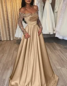 Elegant champagne gold sequined evening gown featuring long sleeves and floor-length satin skirt.