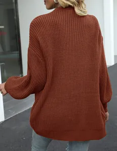 Detail van de grove gebreide textuur en lantaarnmouwen van een bruine oversized trui