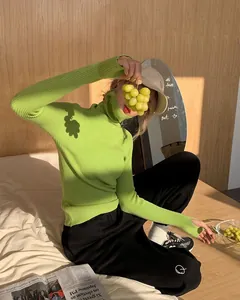 Detail of vibrant lime green ribbed knit turtleneck sweater featuring thumbhole cuffs