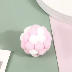 Detailed close-up of a pink and white plush pom-pom cat toy ball showing soft texture.