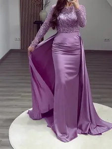 Close-up detail of purple sequin long sleeve evening dress with elegant satin train skirt.