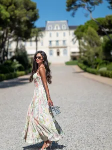 Elegantes Model in einem floralen französischen Retro-Maxikleid in einem Luxusresort.