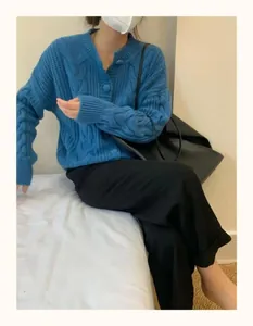 Close-up view of a blue cable-knit cardigan featuring round neck and button details
