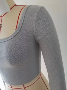 Primo piano della trama a coste grigie del crop top aderente a maniche lunghe.