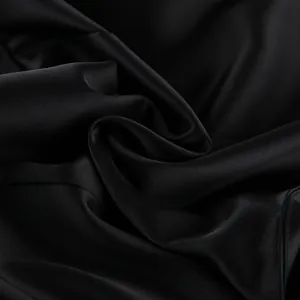 Close-up detail of black satin fabric with elegant glossy finish and soft folds