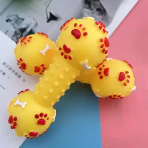 Squeaky dumbbell dog toy in yellow with embossed red paw prints and white bone patterns.