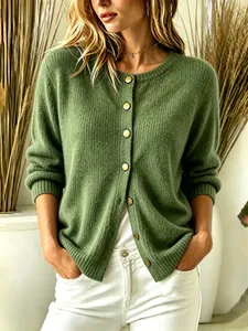 Detail view of a soft green knitted cardigan with golden buttons and ribbed cuffs.
