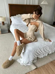 Modelo con un conjunto de descanso beige de 3 piezas con sudadera corta y corsé