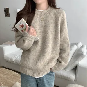 Gros plan de la maille douce d'un pull beige à col rond et coupe ample