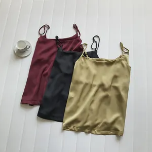 Dettaglio di tre canotte in raso con spalline sottili in bordeaux, nero e oro champagne.