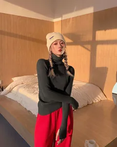 Model wearing a dark green ribbed turtleneck knit sweater in cozy warm sunset lighting