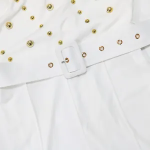 Detailed macro view of a white fashion jumpsuit with gold stud accents and a buckled belt