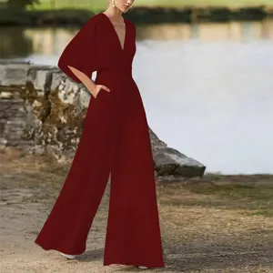 Vista intera di un'elegante tuta bordeaux a gamba larga con scollo a V profondo e tasche