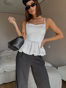 Detailed shot of white satin peplum camisole featuring slim waist and pleated flare