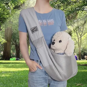 Breathable grey mesh pet sling carrier for small dogs and cats in a park setting.