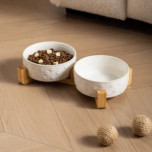 Double ceramic pet feeding bowls with bamboo stand featuring embossed paw print designs