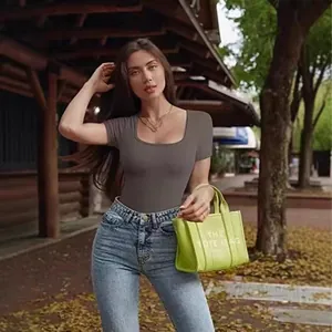 Lifestyle view of a woman in a brown ribbed short-sleeve bodysuit and blue jeans.