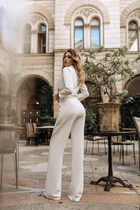 Elegante tuta in raso bianco a maniche lunghe con gambe larghe vista dal lato posteriore