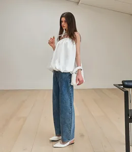 Modèle portant un haut bustier en satin blanc avec un jean en denim bleu ciel.