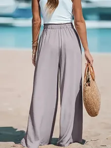 Back view of stylish high-waisted wide-leg trousers with side split detail on a sunny beach