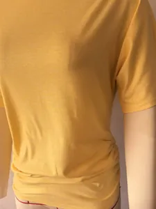 Detailed macro shot of women's slim fit yellow T-shirt with elegant ruched hem texture