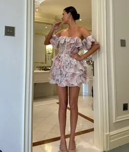 Elegant floral off-the-shoulder ruffled mini dress shown in a luxury indoor setting