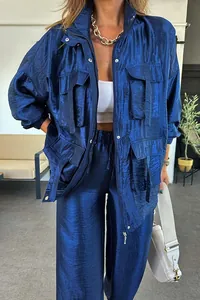 Detail view of a metallic blue cargo jacket with large 3D pockets and shiny fabric