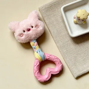 Close-up detail of a pink plush squeaky dog toy featuring a heart-shaped rubber teether handle
