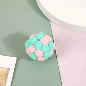 Macro view of colorful plush pom-pom cat toy ball featuring pink and mint green tones