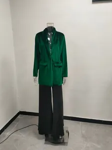 Close-up detail of a women's emerald green velvet blazer with lapel collar and flap pockets