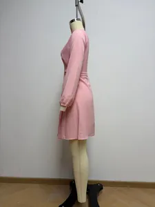 Vista lateral de un vestido cruzado rosa de manga larga en un maniquí de costura