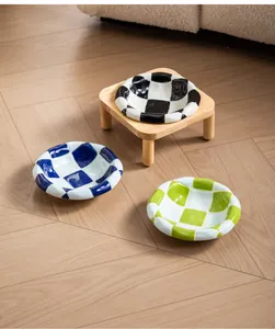 Detailed view of checkered ceramic pet bowls in multiple colors with a wooden stand