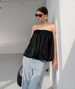 Détail du haut bustier en satin noir chic avec une structure plissée et ample